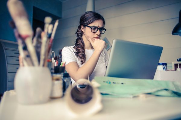 A woman with glasses starting at a computer screen with concern; highlighting overlapping costs in a traditional home sale