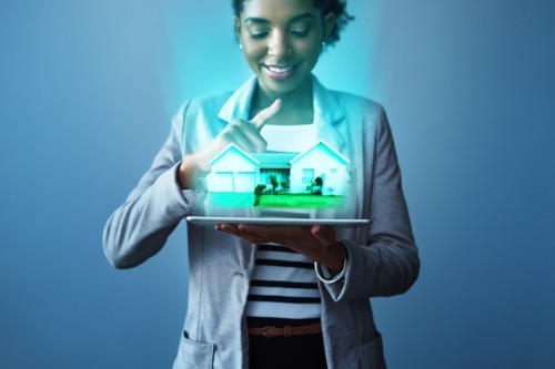 A woman holding a tablet with a 3d hologram of a home, highlighting the Canadian Real Estate Homebuying through the ibuyer program